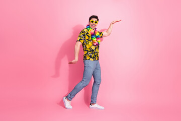 Fototapeta premium Joyful man in colorful summer outfit and sunglass posing on pink background with cheerful expression and confident gestures