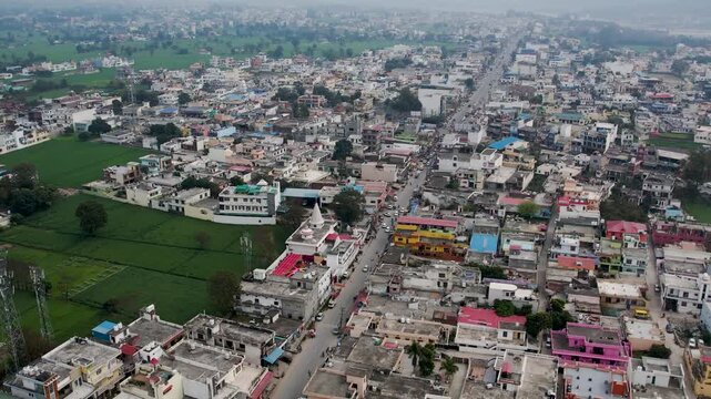 A 4K drone aerial view of Mohali city in Punjab, India, showing a long road with cars and other vehicles in motion, surrounded by residential houses, other buildings, and urban infrastructure