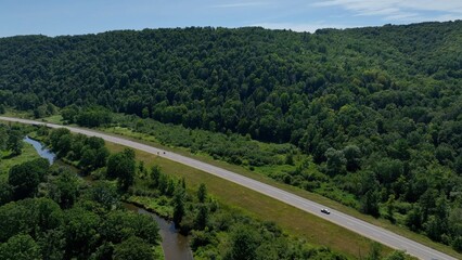 Traveling across rural American countryside driving on country roads past green rolling hills and farmland in New York State near Wallace, NY 