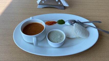 South Indian Breakfast Plate with Idli, Sambhar, Chutney, and Spices on a White Table