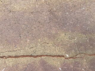 A close-up view of textured stone with natural veins and a mix of earthy colors, showcasing unique patterns and geological features.