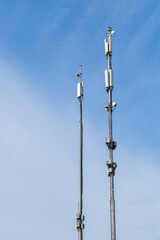 Obraz premium Two communication towers against a clear blue sky, showing infrastructure for modern connectivity and wireless technology