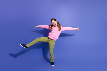 Obraz premium Smiling young girl wearing casual sport style isolated against violet background showing joyful gestures full of energy