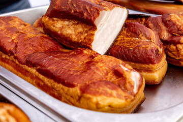 Savory delicacies featuring freshly cooked meat displayed in a metal tray at a bustling outdoor market during midday