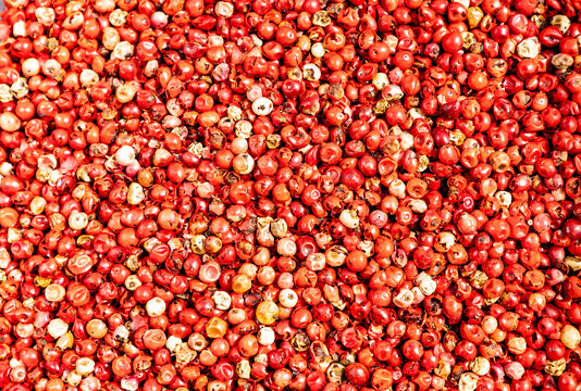Bright red peppercorns scattered across a textured surface for culinary use in cooking or spice blends during a vibrant food preparation session
