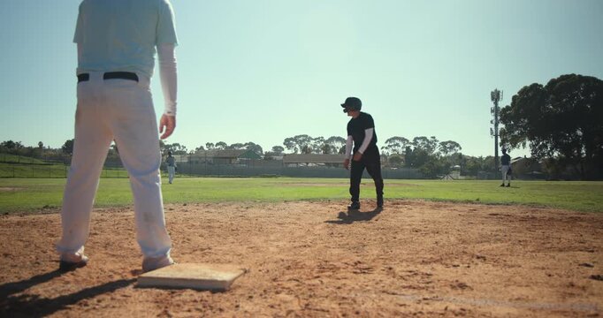 Reacting to pickoff throw, adult male runner shifting on first base at youth field, stealing second