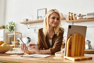 Elegant senior woman engages in creative work while enjoying a bright kitchen setting