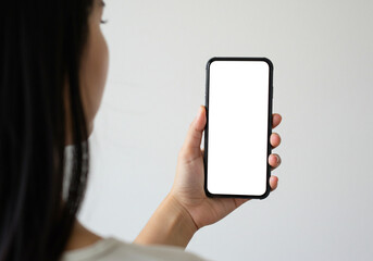 A person holding a smartphone with a blank white screen, seen from over the shoulder. This mockup is suitable for displaying user interfaces or mobile website designs.