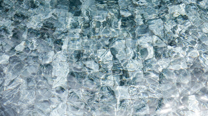 Rippling clear water surface in a serene setting reflecting light during the day