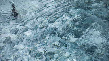 Clear water reflecting sunlight gently ripples in a serene pool during a sunny afternoon in a tranquil outdoor setting