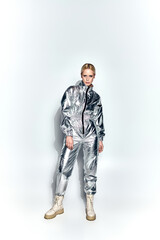 Fototapeta premium Young blonde woman showcases a futuristic outfit in a dynamic studio setting
