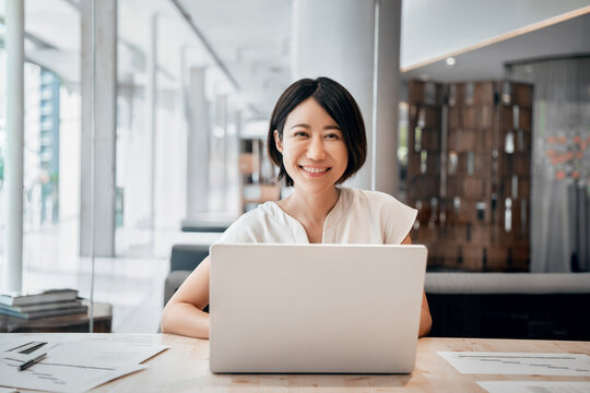 30s middle-aged woman using computer technology for financial bank work online. Mature Asian professional it specialist businesswoman working on laptop pc sitting at desk in office. Portrait at camera