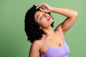 Obraz premium Portrait of a young woman with natural curls and confident pose against a green background, expressing self-love and beauty