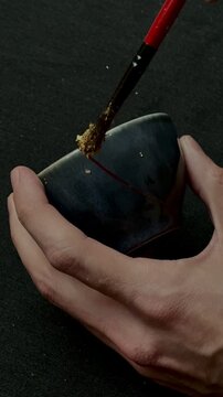 kintsugi gold cracks restoration process, Japanese black bowl fixed with the antique kintsukuroi restoration technique, the beauty of imperfections, representation of a trauma
