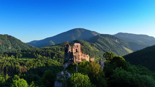 Flying around the rock with the castle ruins on top. Beautiful mountains covered with thick woods at backdrop. Nature of Slovakia.
