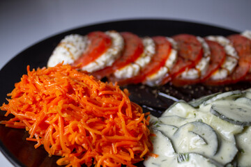 Vegetarian dish, with Caprese salad, grated carrot salad, and cucumber salad with cream vinaigrette.