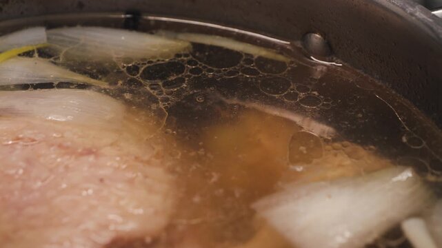 Process of making chicken soup. Boiling broth with meat and vegetables close-up. Soup cooking.