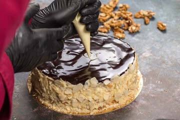 Esterhazy cake. Confectioner Squeezes Cream from Pastry Pouch into Chocolate Glaze