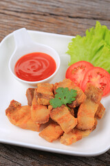 Deep fried Pork Belly with Fish Sauce on a white plate, Garnish with lettuce and tomato