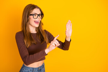 Cheerful young woman gesturing with enthusiasm against a bright yellow background wearing casual stylish fashion