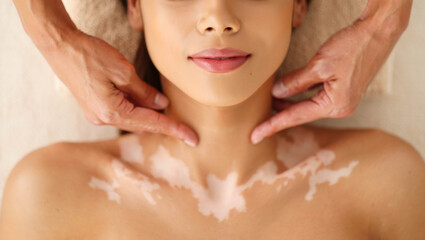 Close-up view of a young woman lying down and receiving a gentle neck massage at a spa, promoting relaxation and well-being