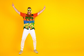 Energetic young man celebrates against a vibrant yellow background showcasing tropical style and summer vibes