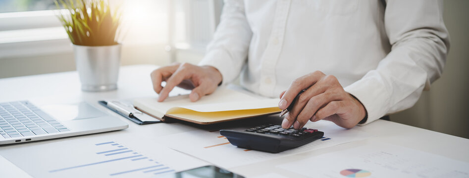Deduction planning, debt asian accountant hand using calculator to calculating money balance from bill and income, cost budget expenses for pay money form personal individual on table at home.