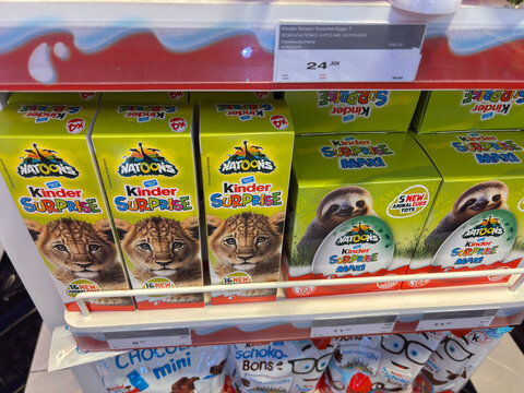 Thessaloniki, Greece - august 09, 2025: rows of kinder surprise eggs, including natoons and maxi variations with animal illustrations, are displayed for sale on a white shelf in a supermarket