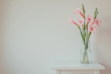 Minimalist white table with pink gladiolus flowers in glass vase against plain wall, simple elegant composition in soft natural style