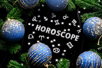 Background with the inscription horoscope on a black background with fir branches and toys.