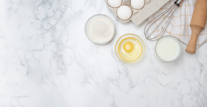 Baking basics with eggs, flour, and milk prepared on a marble countertop for a delicious recipe