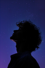 Silhouette of a person looking up at a starry night sky