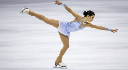 Graceful figure skater elegantly glides across ice under bright arena lights. AI Generated