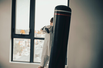 teenager in boxing gloves trains with punching bag