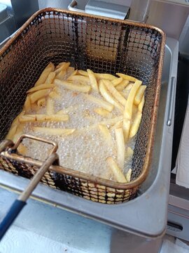 Pommes frittes in der Fritteuse bei der Zubereitung im Gastrobetrieb