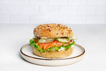Burger or bagel with salmon, cream cheese and cucumber. Healthy breakfast.