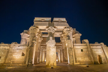 Obraz premium Majestic night view of Temple of Kom Ombo in Egypt showcasing ornate columns with elaborate capitals under dramatic lighting.