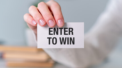 A person holding a white card that says Enter to Win