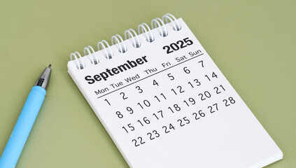 A blue pen sits next to a calendar that says September 2025