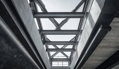 Obraz premium Industrial architecture with exposed steel beams against sky. Concrete, grids, and structure