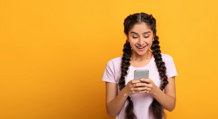 People And Technology Concept. Portrait of smiling cheerful young indian lady using her cellphone,...