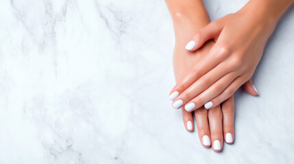 Naklejka premium A close-up of elegantly manicured hands with white nails resting on a smooth marble surface, conveying a sense of beauty and relaxation.