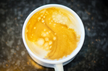 Hot coffee with beautiful latte art in foam reflecting light in white cup