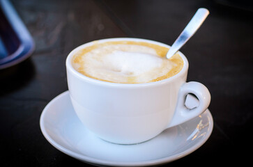 Floating cup of aromatic cappuccino topped with fluffy milk foam