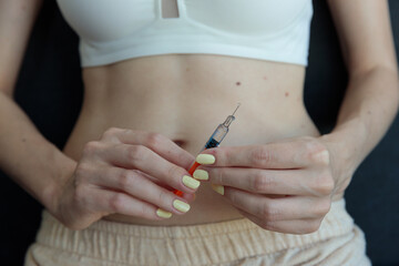 A Close-Up Image of a Woman's Hands Holding a Syringe, Delicately Preparing for a Needle Injection Over a Softly Lit Background in an Intimate Setting