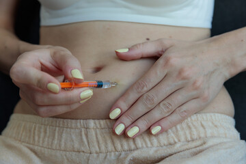 A Close-Up View of a Person Preparing to Inject Medication into Their Abdomen with a Syringe, Signifying Health Care and Medical hormonal stimulation of the ovaries Procedures