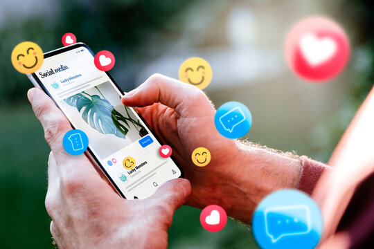 Social media ads on a mobile phone screen with emojis. Man with a smartphone showing an example of a social media ad.