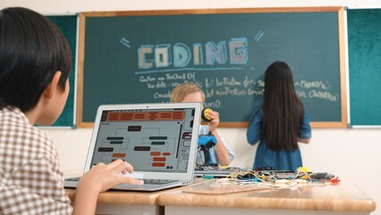 Asian boy coding program while caucasian friend fixing electric board at STEM class. Energetic student standing blackboard while writing coding engineering prompt and programing AI software. Pedagogy.