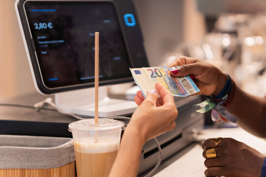 Customer paying with euro banknotes at coffee shop pos terminal