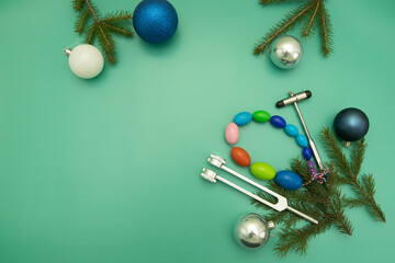 Christmas Medical Instruments with Christmas Tree and blue and silver balls on Green Background. New Year's photo of a medical hammer, orchidometer, tuning fork.